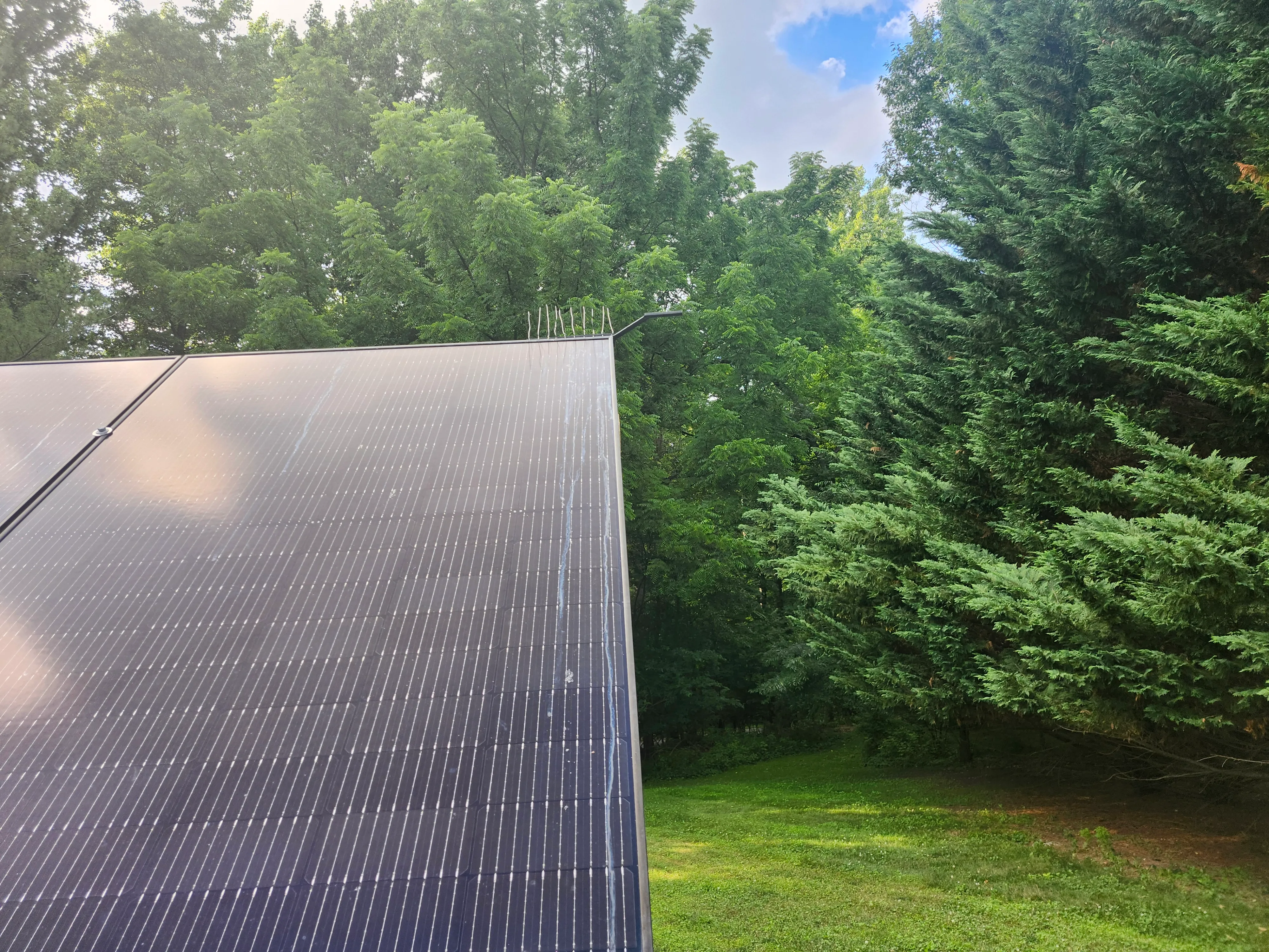 PerchOff mounted on the corner of a live ground-mount solar panel in a yard